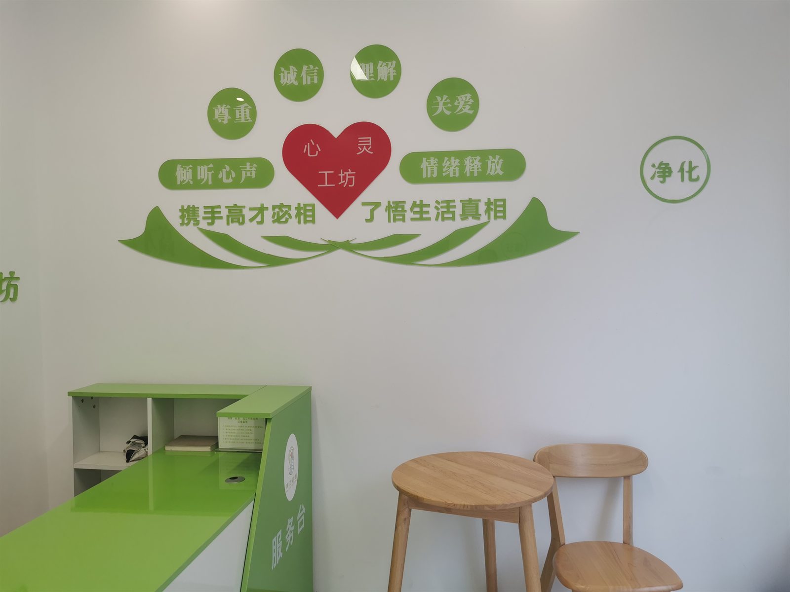 白色墙面上的绿色标语贴饰,含诚信、理解、关爱、倾听心声、情绪释放与心灵工坊等字样